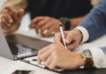 Hand signing a document, representing translation and legal consultancy services